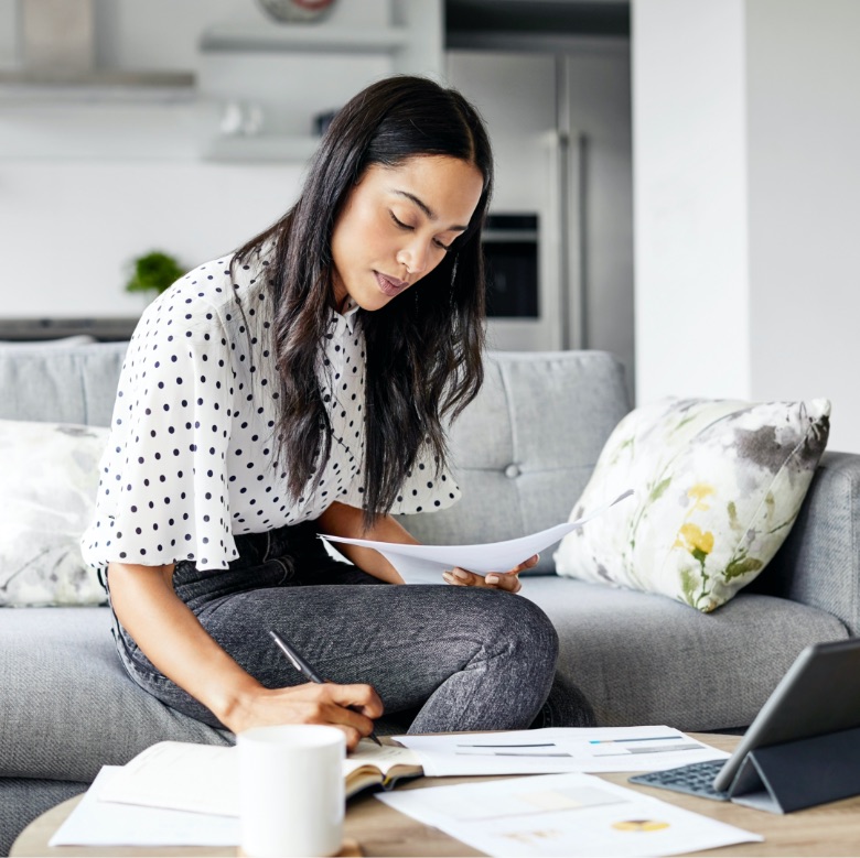 young Canadian Asian woman writing down Term Insurance options on coffee table in living room